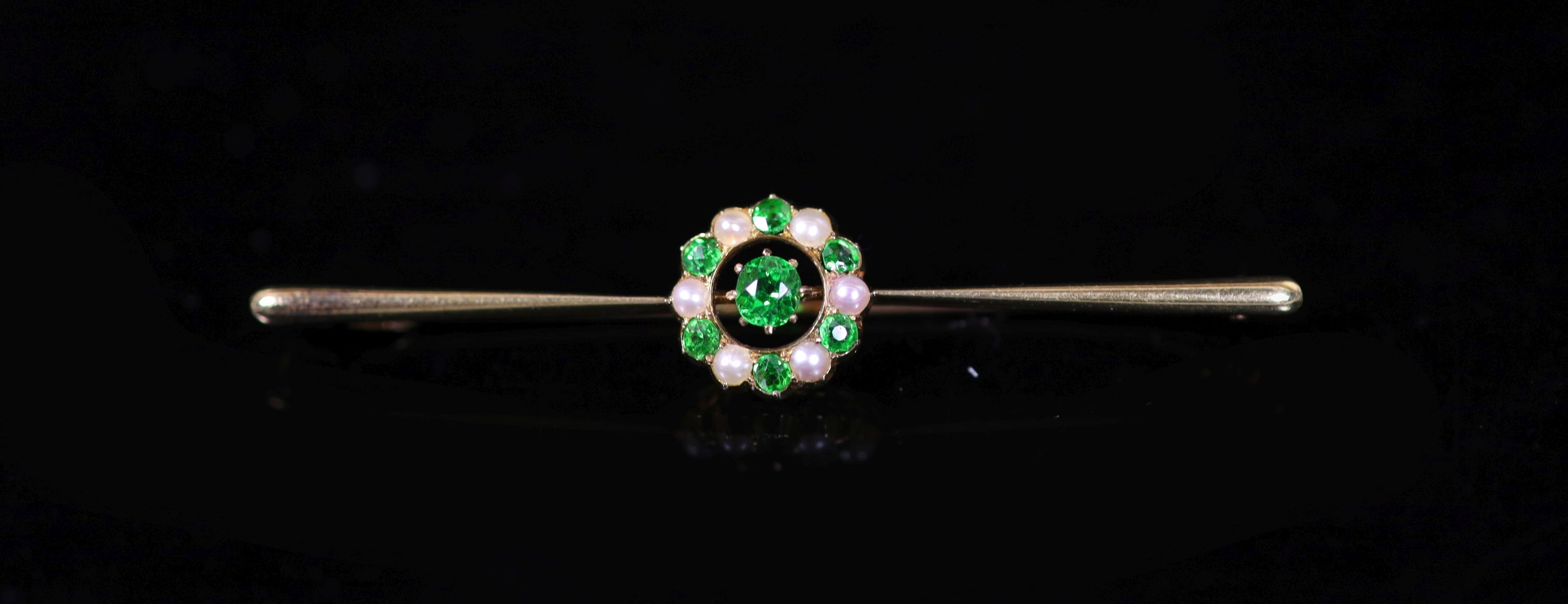 An early to mid 20th century gold, demantoid garnet and seed pearl circular cluster set bar brooch